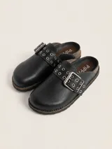 Zueco de cuero negro con diseño de punta redonda y tira ajustable en el empeine con hebilla metálica y ojales decorativos. Interior forrado en cuero y suela con vira reforzada.