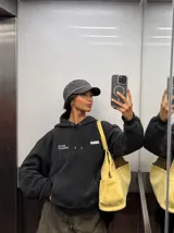 Canguro con capucha gris oscuro, con bolsillo tipo canguro y estampa frontal blanca con texto.