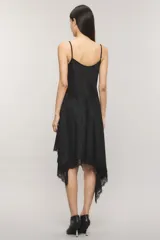 Vestido midi asimétrico de satén jacquard negro con escote lencero, breteles finos regulables, falda amplia con movimiento y terminación de puntilla en el ruedo.