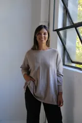 Sweater de punto con acabado brillante, color visón, de corte holgado y mangas largas con puños ajustados. Presenta un diseño con costuras verticales decorativas en el frente.