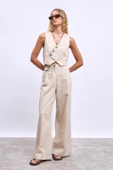 Pantalon de vestir de corte recto y tiro alto, confeccionado en tela de lino en color beige. Presenta pinzas frontales, cierre con botón y detalle de vivos en contraste en la cintura.