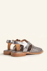 Sandalia plateada de cuero con tiras entretejidas, hebilla lateral y taco bajo.