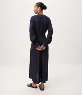 Vestido largo midi estilo chemise de color azul marino, confeccionado en mezcla de viscosa y lino. Presenta escote en V, mangas largas con puños abotonados, cierre frontal de botones y cinturón ajustado del mismo tejido con hebilla redondeada.