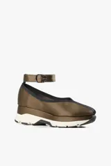 Zapato color marrón con base deportiva, pulsera al tobillo ajustable con hebilla metálica y puntera redondeada.