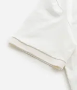 Remera de corte boxy confeccionada en algodón, con cuello polo y cierre frontal de botones. Presenta un diseño estampado en el frente con el número 93, una cruz y la palabra MAD en tipografía gótica.
