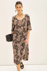Vestido midi de línea A con mangas 3/4, de caída amplia y tejido liviano. Confeccionado en jersey modal estampado con motivos florales en tonos rojos, blancos y negros sobre un fondo gris oscuro.