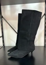 Botas altas de caña ancha en símil gamuza color negro, con diseño de punta fina y tacón fino bajo tipo kitten heel.