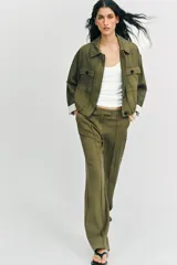 Chaqueta corta de color verde militar, con cuello solapa, bolsillos delanteros con solapa y cierre frontal de botones ocultos. Presenta mangas amplias con vuelta en los puños que muestran un forro a rayas.