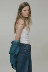 Jean de tiro alto con corte wide leg, confeccionado en denim de algodón rígido. Presenta diseño clásico de cinco bolsillos, cierre frontal con botón y acabado de lavado azul medio con efecto desgastado.
