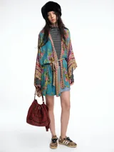 Kimono de corte amplio con mangas anchas, confeccionado en tela con mezcla de estampados florales y geométricos en tonos azules, rosados y dorados. Incluye un cinturón fino del mismo tejido para ajustar a la cintura.