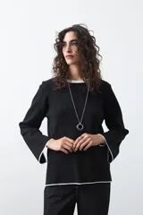 Sweater de tejido de punto con silueta recta y calce relajado. Presenta un diseño liso en color negro con detalles de vivos en contraste color blanco en el cuello redondo, los puños y el ruedo.