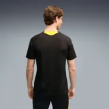 Camiseta de fútbol Puma Cap Tr. Jersey, de color negro con detalles en amarillo en los hombros y cuello. Presenta un sutil diseño gráfico en relieve sobre el tejido y el logo de la marca junto al escudo del Club Atlético Peñarol en el pecho.
