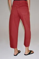 Jeans capri de tiro medio y pernera balloon, color rojo ladrillo. Confeccionados en denim, cuentan con trabillas en la cintura, bolsillos delanteros y traseros, y cierre frontal con cremallera y botón metálico.