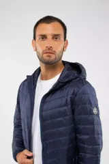 Campera puffer azul marino con diseño capitoneado, capucha integrada, cierre frontal y bolsillos laterales con cierre. Presenta puños elásticos y logo aplicado en la manga.