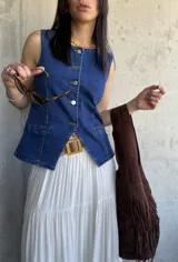 Chaleco de denim azul con escote en V y cierre frontal con botones. Tiene dos bolsillos frontales a la altura de la cintura.