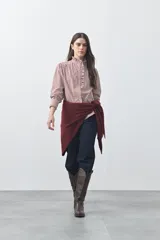 Camisa de manga larga a rayas verticales en tonos blanco y bordó, con cuello alto y detalle de volados frontales. Presenta puños con volados y un corte fluido.