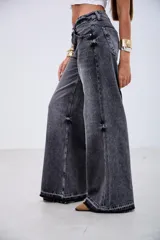 Pantalón de jean estilo wide leg en color negro con efecto lavado. Presenta un corte holgado, tiro medio y costuras reforzadas a lo largo de las piernas, con un ruedo deshilachado y desgastado.