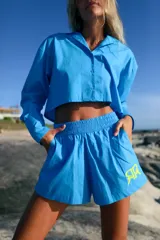 Camisa de manga larga confeccionada en poplín de algodón, con diseño a la cintura y canesú estampado con el logo de la marca en color amarillo neón.