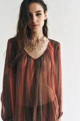 Camisa semitransparente de manga larga con diseño de rayas verticales en tonos marrones y naranjas, escote en V y cierre frontal con botones.