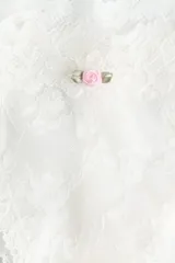 Pack de dos bombachas brasileras de encaje blanco con cintura baja, refuerzo forrado y corte alto en la parte trasera. Una de las bombachas tiene pequeños detalles bordados de flores rosadas.