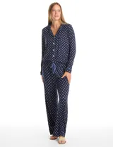 Conjunto de pijama de dos piezas con estampado animal print. La parte superior es una camisa de manga larga con cuello solapa, escote en V, cierre frontal con botones y bolsillo aplicado. El pantalón cuenta con cintura elástica y lazo de ajuste.