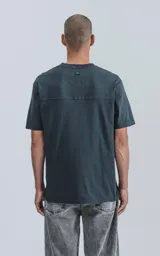 Remera de manga corta con cuello redondo y calce regular, confeccionada en algodón premium. Presenta un diseño minimalista con recorte en la espalda.
