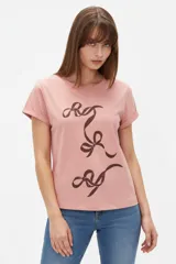 Remera de manga corta color rosado con cuello redondo y estampado frontal de moños en tono marrón.