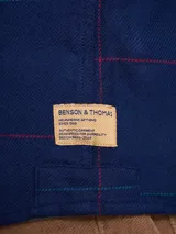 Camisa de manga larga en color azul noche con un patrón de cuadros finos en tonos rojos y verdes. Presenta cuello clásico, cierre frontal con botones y un bolsillo en el pecho con solapa.