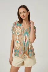 Blusa de lino con diseño estampado multicolor en tonos tostado, turquesa y rosado, corte holgado, mangas cortas y escote en V.