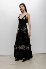 Vestido largo negro con escote en V y tirantes finos. Presenta un diseño de paneles horizontales que alternan bandas de lentejuelas negras brillantes con bandas decoradas con aplicaciones de lentejuelas iridiscentes en forma de pétalos.