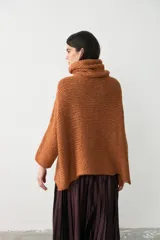 Sweater tipo poncho de tejido de punto grueso en color ocre, con cuello alto holgado y diseño de corte amplio con aberturas laterales en el ruedo.