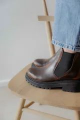 Botas tipo Chelsea de cuero con acabado vintage, diseño de caña media con paneles elásticos laterales y suela track robusta.