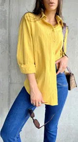 Camisa amarilla de manga larga con cuello clásico y cierre frontal con botones.