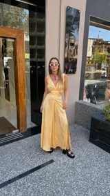 Vestido largo color durazno con escote pronunciado en V y aberturas laterales en la cintura. Presenta un drapeado frontal y falda con tajo lateral.