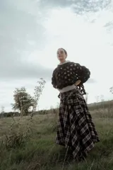 Buzo de tejido de punto calado con diseño de red, cuello redondo y mangas largas abullonadas. Presenta una textura jaspeada en tonos gris y blanco.