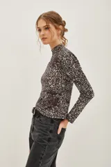 Polera de manga larga con cuello alto, confeccionada en tejido de algodón con estampado floral tipo liberty en tonos oscuros.