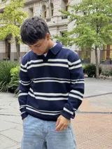 Buzo tejido de punto con diseño de rayas horizontales en azul marino y blanco, cuello polo y mangas largas.