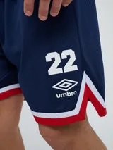 Short deportivo Umbro del Club Nacional de Football, modelo Match para hombre. Diseño en color azul marino con tejido de malla, detalles en blanco y rojo en los laterales y el escudo del club bordado.