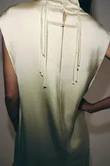 Vestido midi de Zara Woman Collection confeccionado en hilatura de viscosa con tejido satinado, de color beige. Presenta cuello subido, diseño sin mangas (manga sisa), bajo recto con aberturas laterales y cierre en la espalda con alamares.
