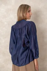 Camisa de organza blanca con cuello mao, diseño de manga larga tipo murciélago y cierre frontal con botones. Presenta un corte holgado y fluido.