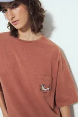 Remerón de manga corta color terracota con efecto gastado, silueta amplia y bolsillo aplicado con bordado de perro salchicha.