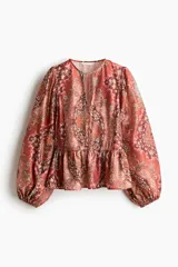 Blusa de viscosa con estampado paisley en tonos rojizos, cuello redondo con escote en V y tiras finas con cuentas decorativas. Cuenta con mangas globo largas terminadas en elástico fino y detalle de peplum acampanado en el ruedo.