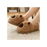 Pantuflas cerradas de peluche suave color marrón, con diseño de capibara que incluye orejas y nariz en relieve. Tienen suela antideslizante.
