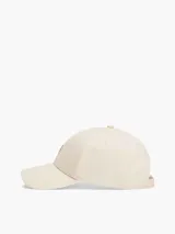 Gorra de béisbol color beige claro, confeccionada en algodón peinado. Presenta el logo de Tommy Hilfiger en dorado en el frente y hebilla metálica ajustable en la parte trasera.