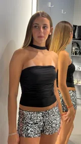 Top negro strapless, ajustado al cuerpo, con detalle de frunces horizontales en la parte delantera. Incluye un choker negro incorporado.