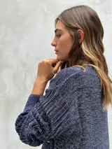 Sweater de punto color gris oscuro con hilos de lurex plateados, cuello redondo y mangas largas abullonadas con puños ajustados.