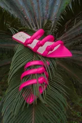 Sandalias bajas fucsia de cuero con tres tiras gruesas sobre el empeine, cada una con un nudo decorativo.