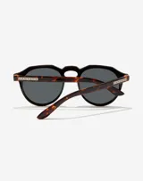 Lentes de sol Hawkers unisex, modelo Warwick, con montura redonda negra y patillas Carey.