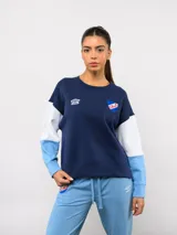 Buzo de cuello redondo Umbro del Club Nacional de Football, con diseño de bloques de color en azul marino, blanco y celeste. Presenta el logo de la marca y el escudo del club en el pecho.
