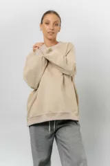 Buzo oversize de algodón frizado color beige, con cuello redondo, puños y cintura tejidos. Presenta un bordado tono sobre tono de Garfield en el frente.